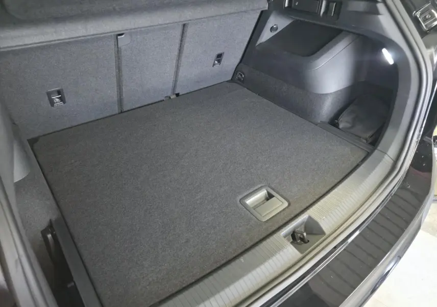 Coffre spacieux du Volkswagen Tiguan noir 2025, vue intérieure arrière avec plancher plat et éclairage intégré.