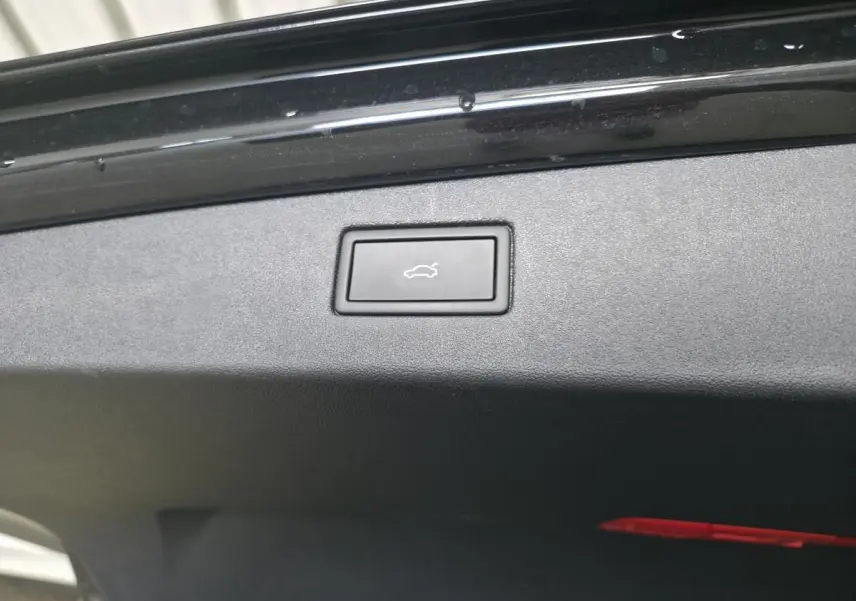 Bouton d'ouverture électrique du hayon sur le bord intérieur du coffre d'un Volkswagen Tiguan noir.