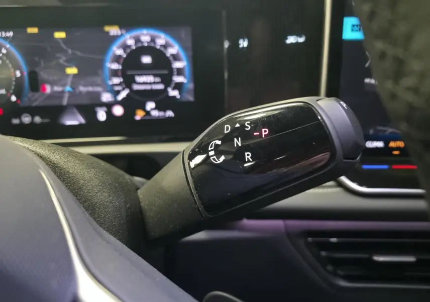 Gros plan sur la commande de boîte automatique noire du Volkswagen Tiguan 2025, avec tableau de bord numérique en arrière-plan.