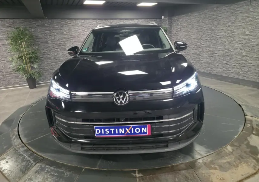 Volkswagen Tiguan noir vue de face en intérieur avec phares LED allumés et calandre chromée.