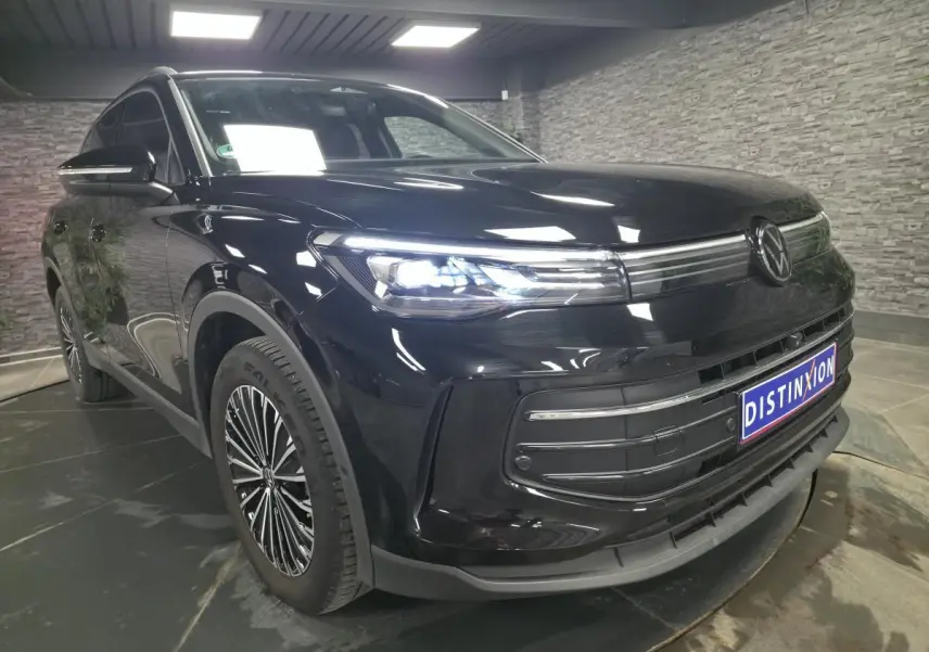 Volkswagen Tiguan noir 2025 en 3/4 avant droit avec phares LED allumés et jantes alliage distinctives.