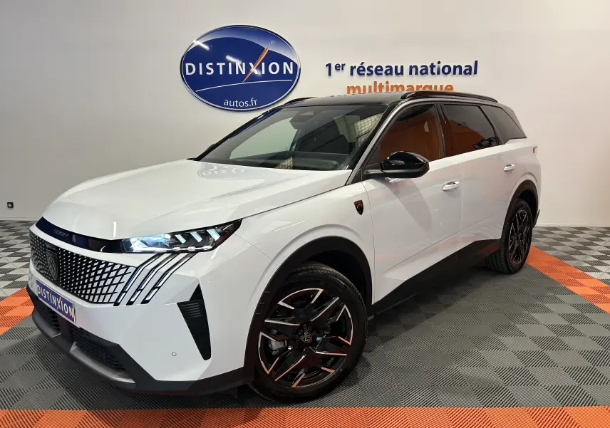 Peugeot 5008 Hybrid blanc vue 3/4 avant droit, avec jantes noires et toit noir brillant en intérieur showroom.