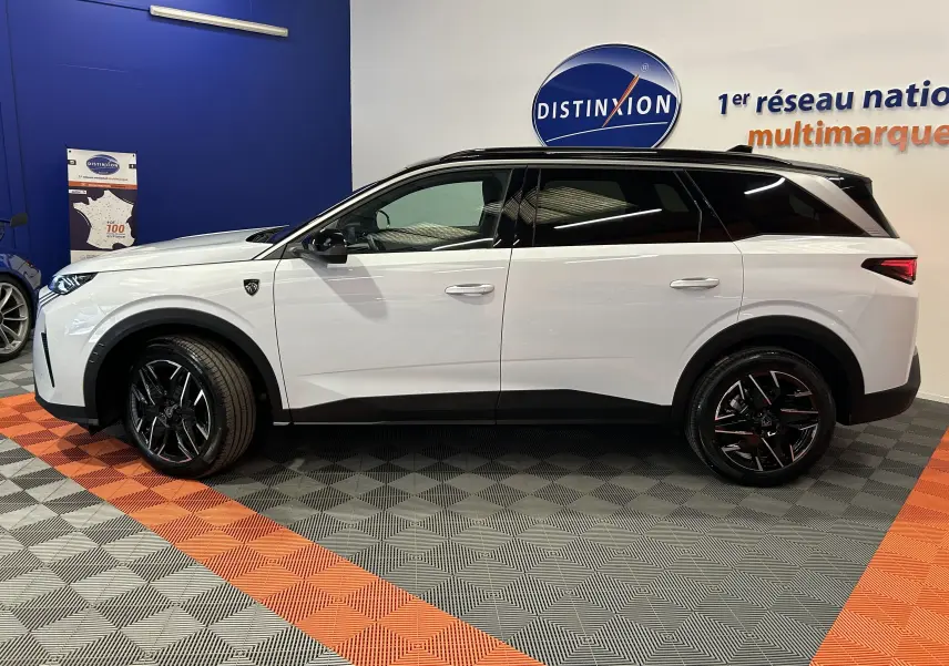 Vue de profil côté gauche d’un Peugeot 5008 Hybrid blanc avec toit noir et jantes noires en concession.