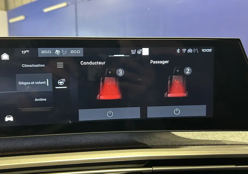 Écran tactile intérieur du Peugeot 5008 Hybrid 2025 montrant le réglage chauffant des sièges conducteur et passager.