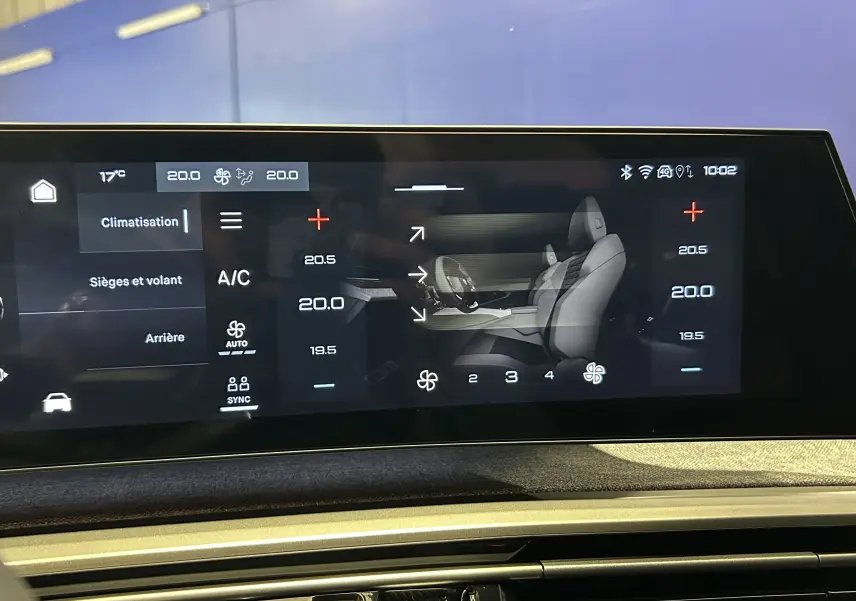 Vue rapprochée de l'écran tactile intérieur du Peugeot 5008 blanc, affichant les réglages de climatisation et sièges.