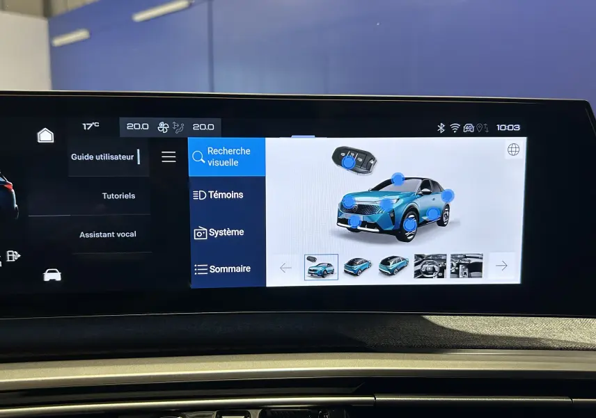 Écran tactile intérieur montrant l'interface multimédia avec une voiture bleue en 3/4 avant et des icônes interactives.