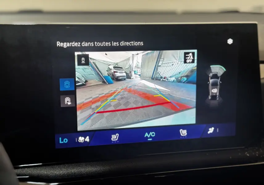 Écran tactile intérieur montrant la caméra de recul et l'aide au stationnement de la Renault Clio gris clair.