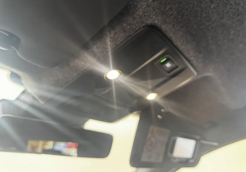 Plafonnier intérieur allumé avec miroir de courtoisie ouvert sur Renault Clio gris clair, vue vers le toit et pare-soleil.
