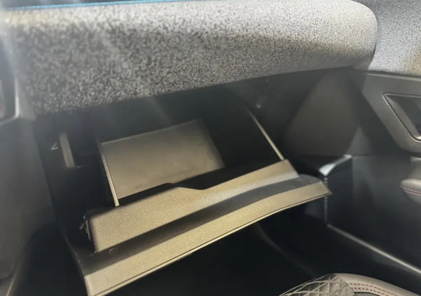 Gant de boîte à gants ouvert côté passager dans l’habitacle sombre d’une Renault Clio gris clair 2026.