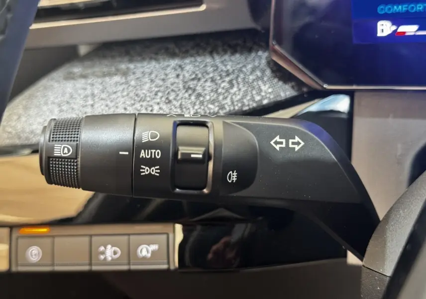 Gros plan sur la commande des feux et clignotants à gauche du volant dans l’habitacle de la Renault Clio gris clair 2026.