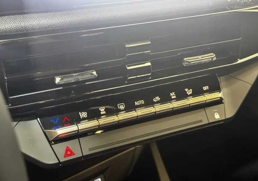 Gros plan sur la console centrale noire de la Renault Clio gris clair 2026, avec commandes climatisation et bouton hazard.