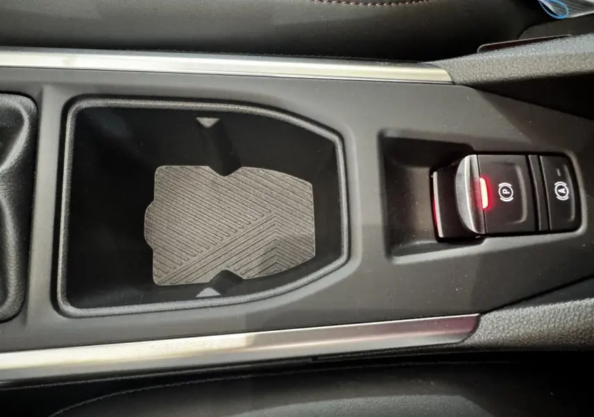Gros plan sur la console centrale noire de la Renault Clio gris clair, avec frein à main électrique et bouton start/stop.