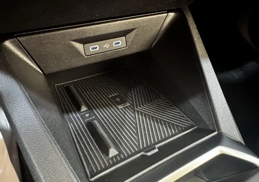 Gros plan sur la console centrale de la Renault Clio gris clair 2026, montrant le chargeur sans fil et ports USB-C.