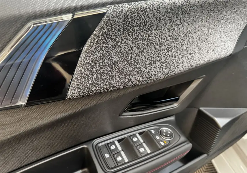 Détail de la porte intérieure côté conducteur de la Renault Clio gris clair, avec commandes électriques et tissu texturé.