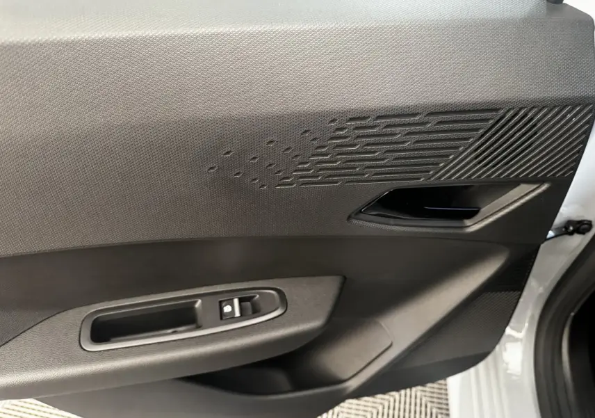 Gros plan sur la porte avant droite grise de la Renault Clio 2026, avec poignée intérieure et commande de vitre électrique.