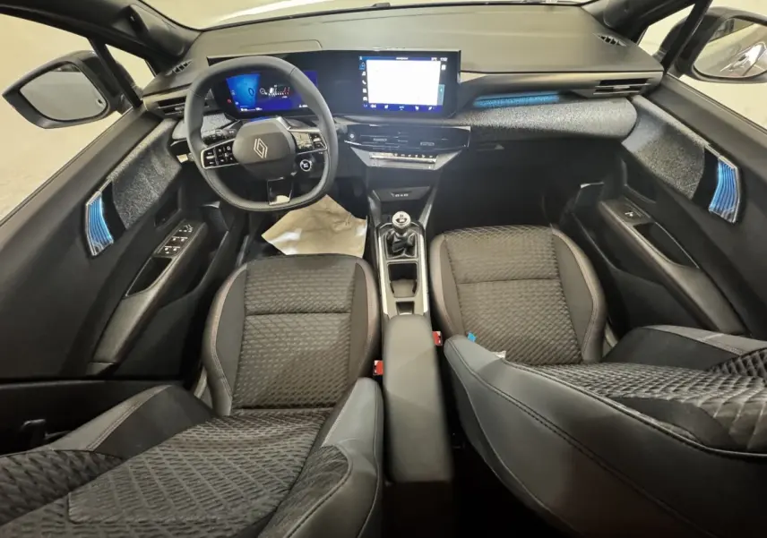 Vue intérieure avant de la Renault Clio Techno TCe 115, sièges noirs, volant multifonctions et écran tactile central.