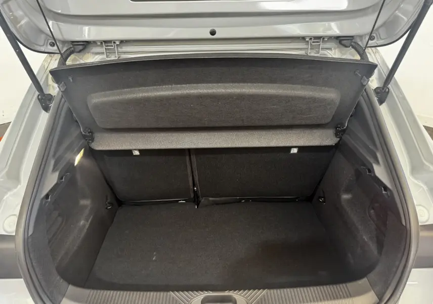 Coffre ouvert vu de l'arrière d'une Renault Clio gris clair 2026, montrant l'espace de chargement vide et la tablette de coffre.