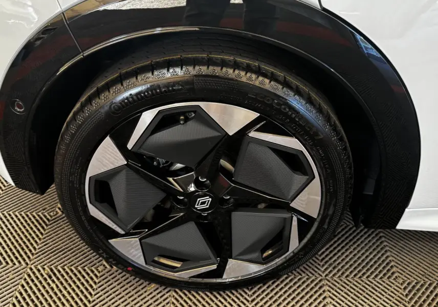Gros plan sur la roue avant droite de la Renault Clio gris clair, jante noire et argentée au design géométrique.