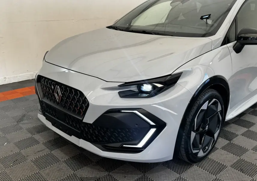 Vue 3/4 avant droit d'une Renault Clio Techno TCe 115 gris clair avec phares LED et jantes noires distinctives.