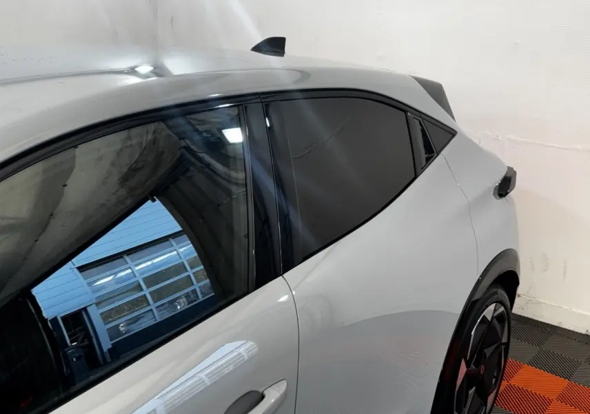 Vue latérale gauche rapprochée de la Renault Clio Techno TCe 115 gris clair avec vitres teintées et jantes noires.