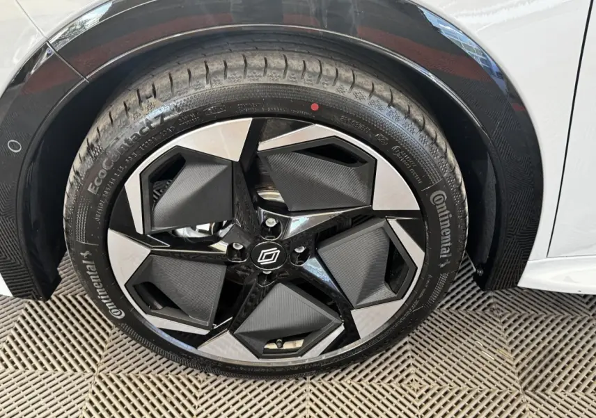 Gros plan sur la roue avant droite de la Renault Clio gris clair, avec jante noire et argent au design géométrique.