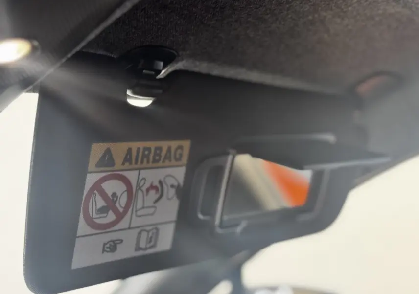 Détail du pare-soleil côté conducteur avec miroir et avertissement airbag dans Renault Clio gris clair 2026.