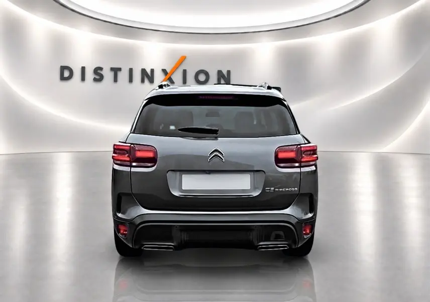 Vue arrière d'un Citroën C5 Aircross gris 2025 avec feux LED et barres de toit en showroom lumineux.