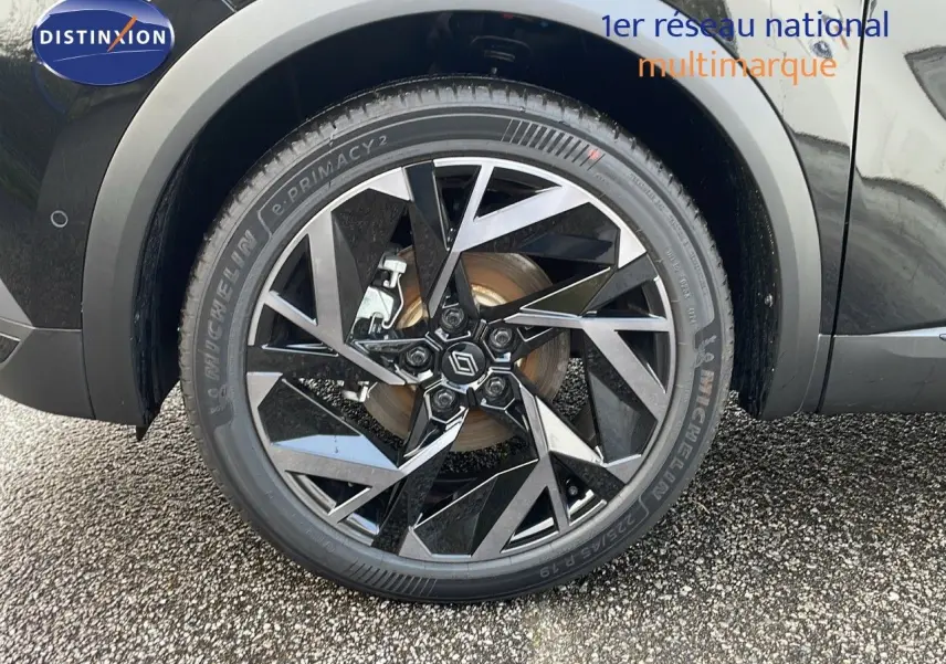 Gros plan sur la roue avant droite du Renault Captur noir étoile avec jante alu bicolore au design géométrique.