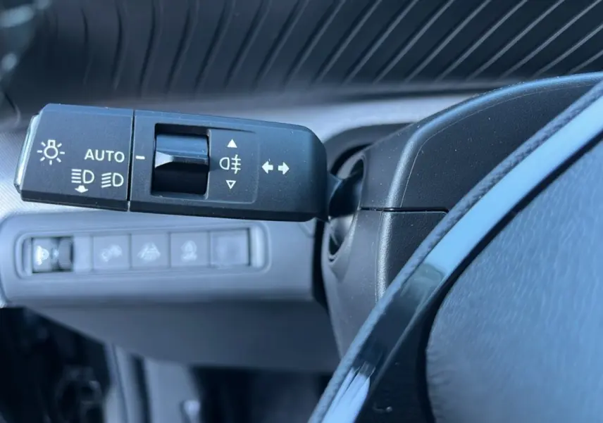 Gros plan sur la commande des feux et clignotants à gauche du volant cuir dans le tableau de bord noir du Citroën C3 Aircross 2025.