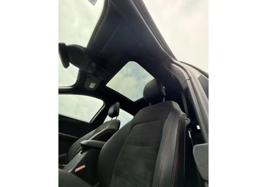 Vue intérieure du Ford Kuga 2023 noir Agathe, sièges avant avec surpiqûres rouges et toit ouvrant panoramique.