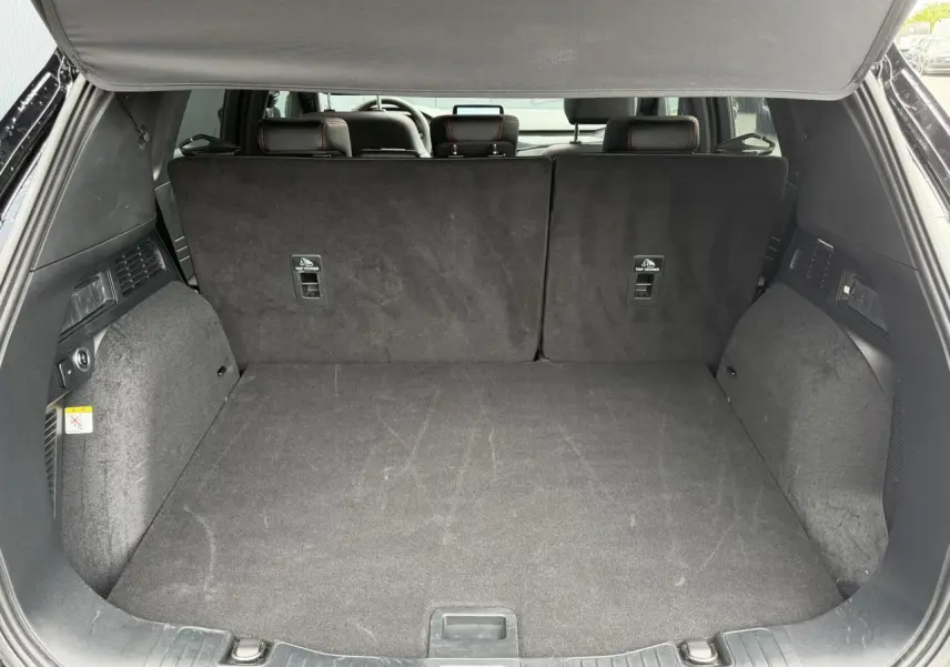 Coffre ouvert vu de l'arrière d'un Ford Kuga noir Agathe, montrant l'espace de chargement et la banquette arrière relevée.