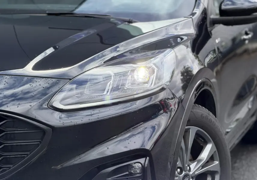 Vue 3/4 avant droit du Ford Kuga noir Agathe avec phares LED allumés et jantes alliage 18 pouces ST-Line.