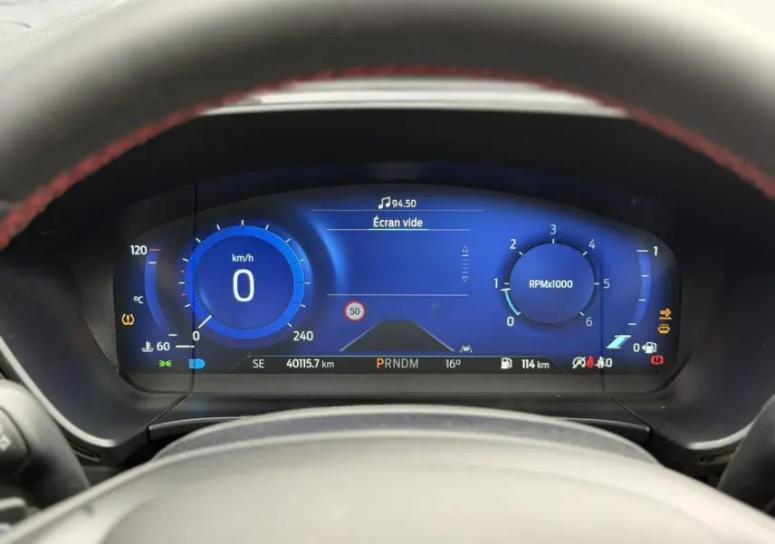 Vue rapprochée du combiné d'instrumentation numérique bleu du Ford Kuga noir, affichant vitesse et compte-tours.