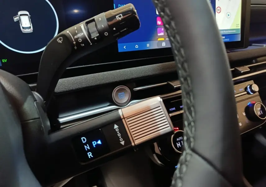 Gros plan intérieur sur le volant cuir et la commande de boîte auto du Hyundai Tucson 1.6 Hybrid gris foncé, avec écran tactile en arrière-plan.