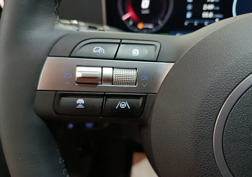 Gros plan sur les commandes multifonctions à gauche du volant cuir du Hyundai Tucson gris foncé 2025 hybride.