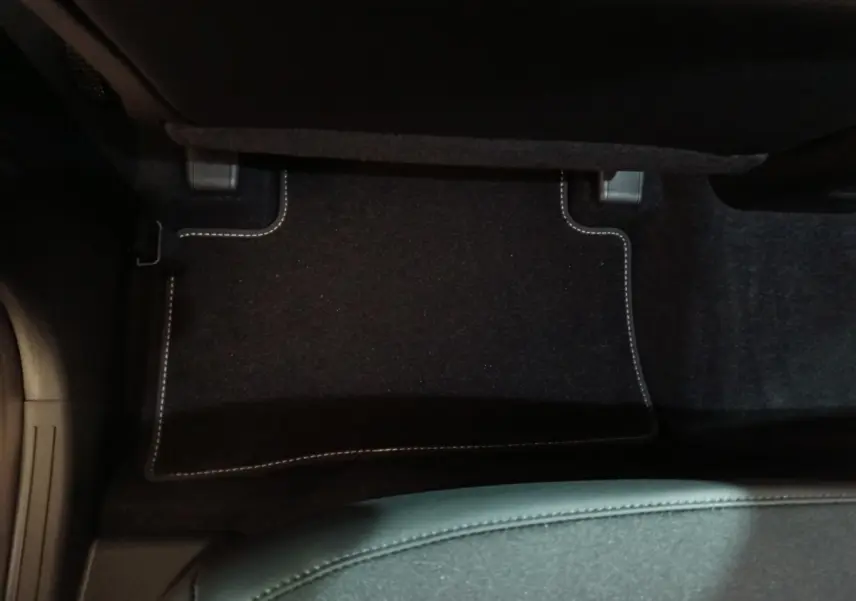 Vue plongeante sur le tapis de sol noir avec surpiqûres blanches côté passager du Hyundai Tucson gris foncé 2025.
