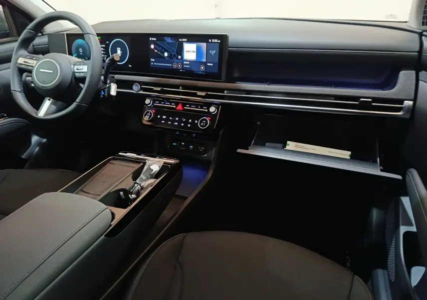 Intérieur du Hyundai Tucson 2025, vue côté passager, tableau de bord noir avec écran tactile 12,3 pouces et boîte à gants ouverte.