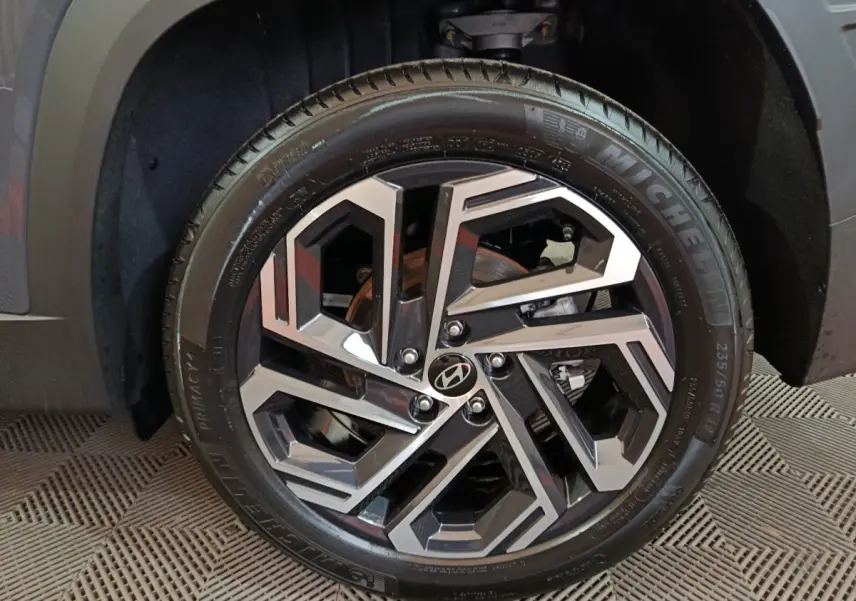 Gros plan sur la roue avant droite du Hyundai Tucson gris foncé, jante alliage au design géométrique moderne.