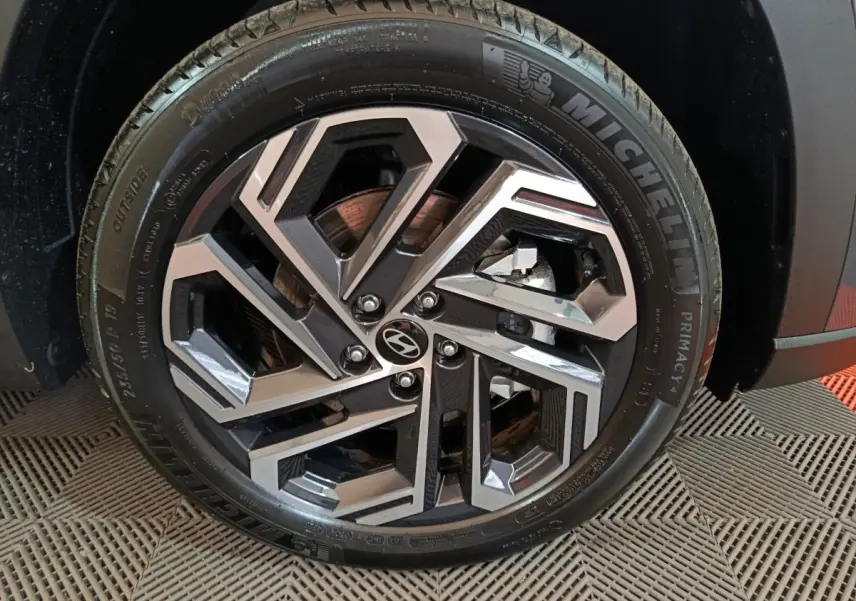 Gros plan sur la roue avant droite du Hyundai Tucson gris foncé, avec jante alliage au design géométrique.