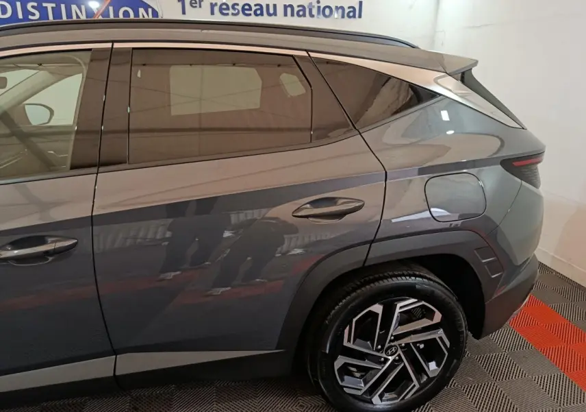 Vue latérale droite du Hyundai Tucson gris foncé 2025, mettant en valeur la jante alliage au design moderne et la ligne de caisse anguleuse.