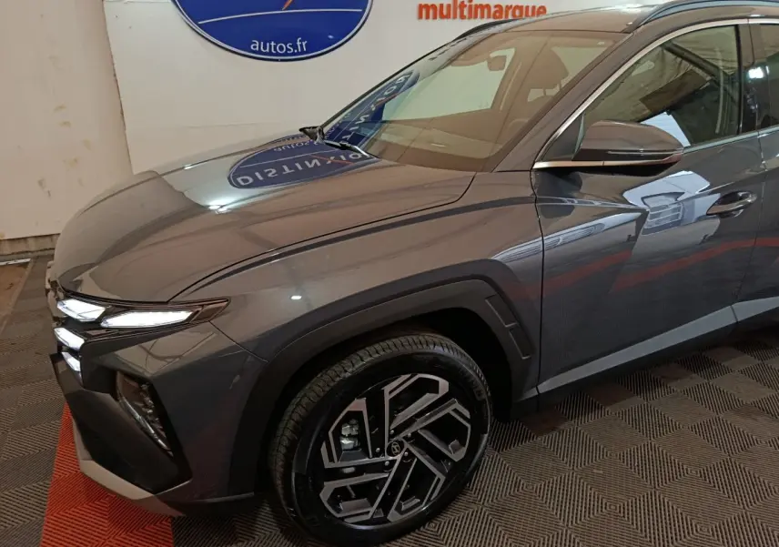 Vue 3/4 avant droit du Hyundai Tucson gris foncé avec ses phares LED et jantes alliage distinctives.