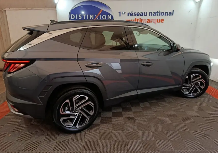 Vue latérale droite du Hyundai Tucson 1.6 Hybrid gris foncé, soulignant ses jantes alliage au design moderne et ses lignes anguleuses.