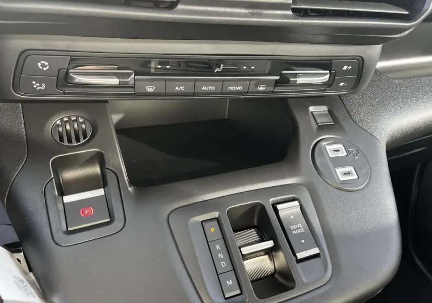 Vue rapprochée de la console centrale noire du Citroën Berlingo 2026, avec commandes climatisation et levier de boîte automatique.