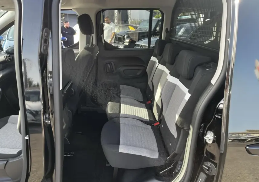 Vue intérieure côté droit du Citroën Berlingo noir Perla Nera, montrant la banquette arrière trois places en tissu bicolore.