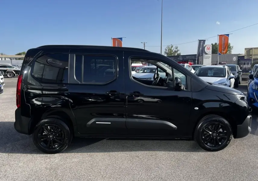 Vue latérale droite d'un Citroën Berlingo noir Perla Nera avec jantes noires et vitres teintées, sur parking extérieur.