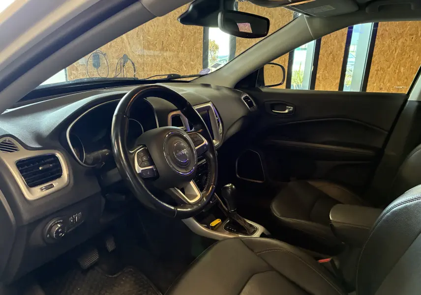 Vue intérieure côté conducteur du Jeep Compass 2021, volant cuir multifonctions et tableau de bord noir avec écran tactile.