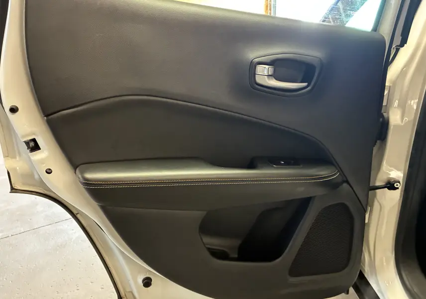 Gros plan sur la porte arrière gauche ivoire du Jeep Compass avec garniture noire et haut-parleur intégré.