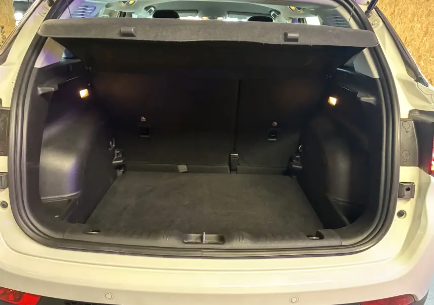 Coffre ouvert vu de l'arrière d'un Jeep Compass ivoire, montrant l'espace de chargement et l'éclairage intérieur.