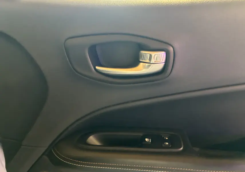 Gros plan sur la poignée intérieure et les commandes de verrouillage de la porte côté conducteur du Jeep Compass ivoire 2021.