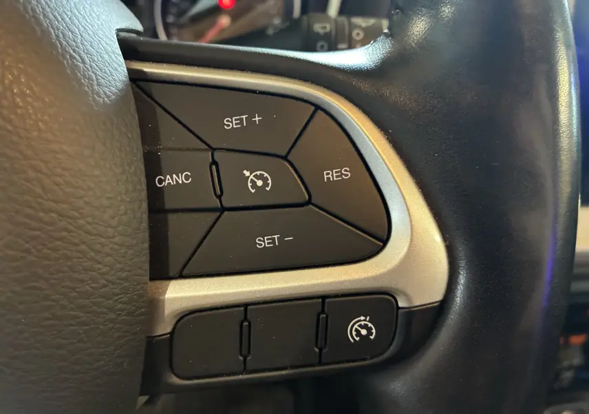 Gros plan sur les commandes du régulateur de vitesse au volant cuir noir du Jeep Compass ivoire, version Longitude 2021.